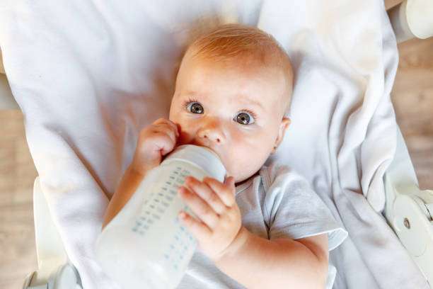 Cute little newborn girl drinking milk. bottle warmer