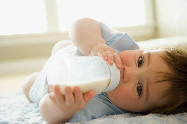 The baby is drinking milk from a bottle warmer.
