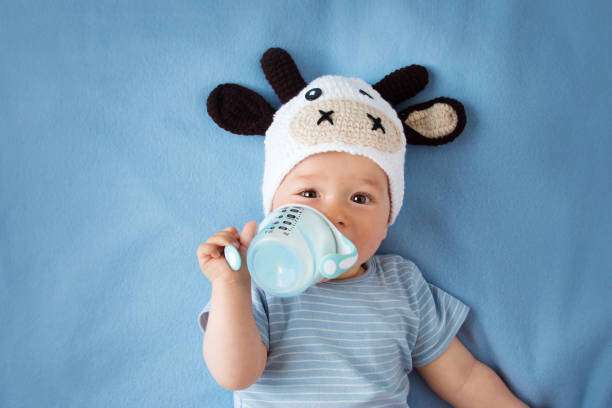 cute baby in a cow hat drinking milk, bottle warmer