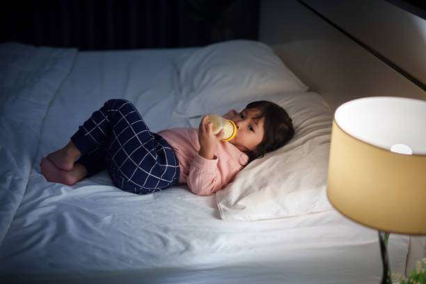 toddler baby girl drinking milk from a bottle warmer