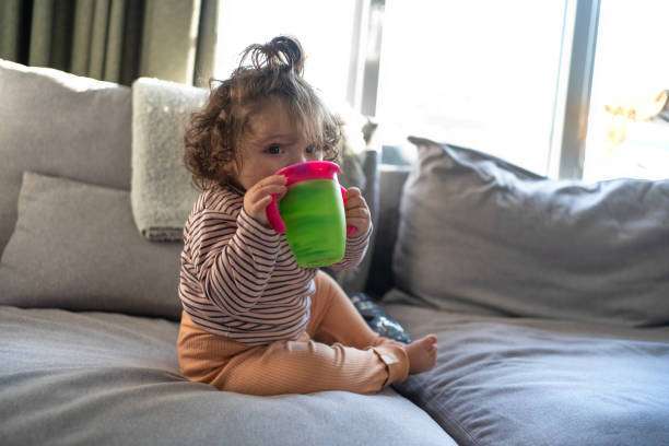A curly-haired baby girl uses a bottle warmer.