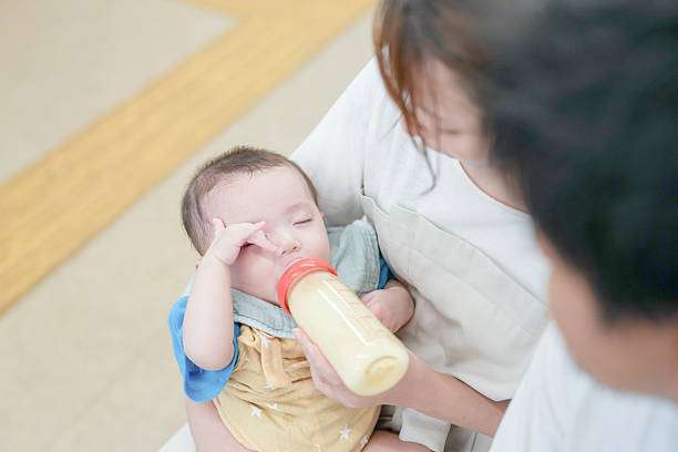 toddler baby girl drinking milk from a bottle warmer