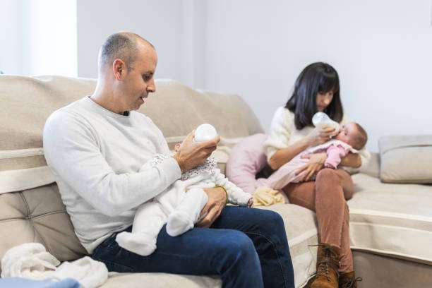 Mother and father feeding milk to their babies on the sofa in the living room. bottle warmer