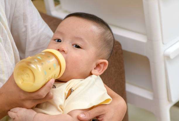 A curly-haired baby girl uses a bottle warmer.