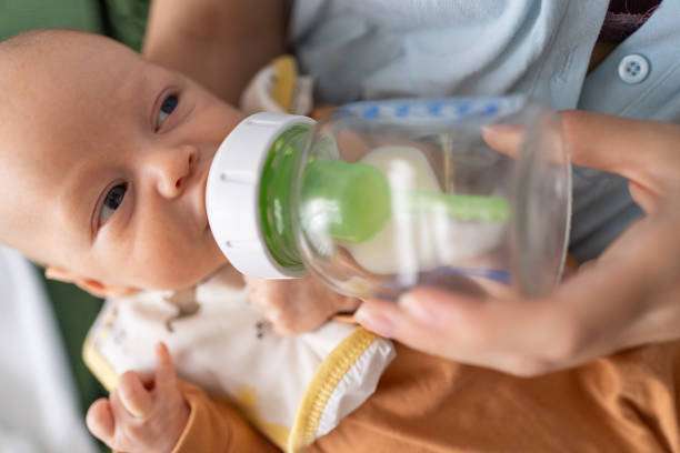 A curly-haired baby girl uses a bottle warmer.