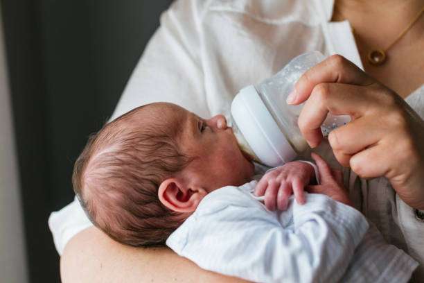 A curly-haired baby girl uses a bottle warmer.