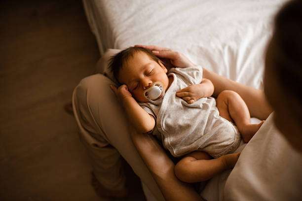 A curly-haired baby girl uses a bottle warmer.
