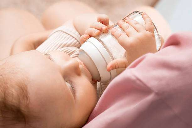 toddler baby girl drinking milk from a bottle warmer