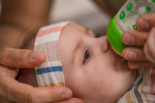 Grandfather holding and feeding his newborn grandson with a milk bottle in a park. bottle warmer