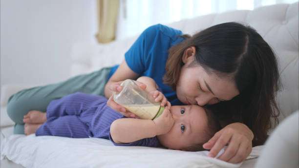 A mother lulls her little child to sleep with a bottle warmer