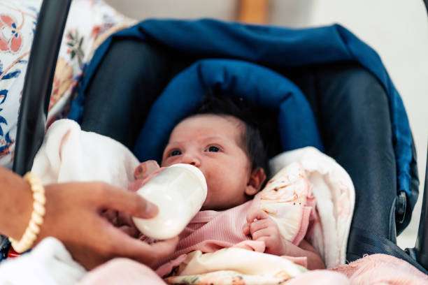 A curly-haired baby girl uses a bottle warmer.
