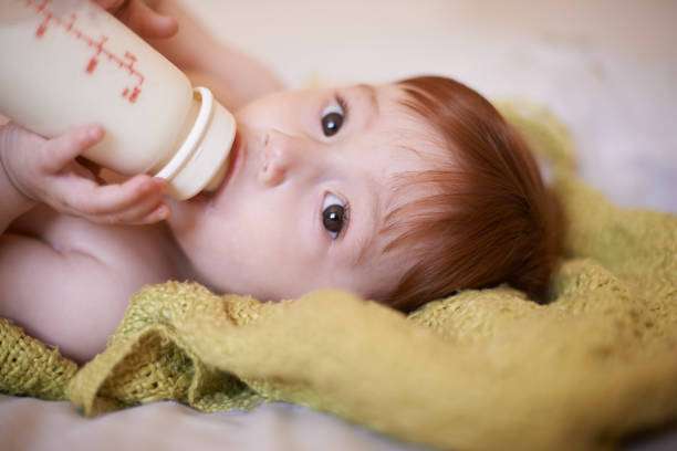 A curly-haired baby girl uses a bottle warmer.