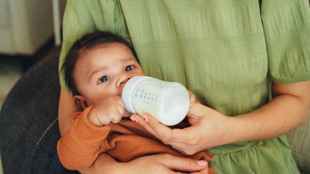 A curly-haired baby girl uses a bottle warmer.