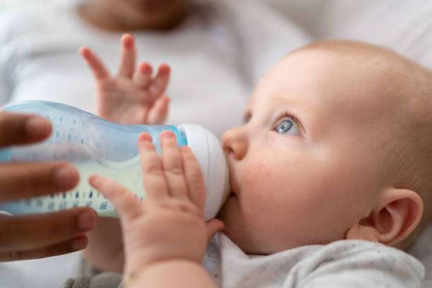Baby boy drinking milk from milk bottle warmer