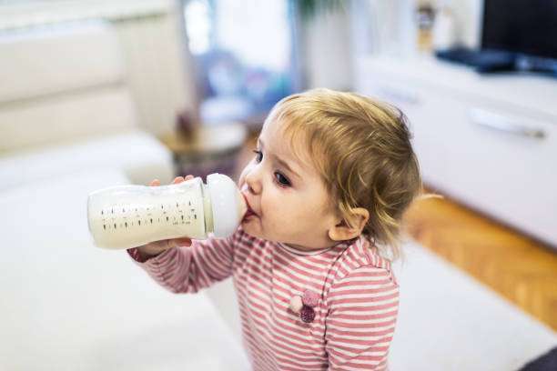 A curly-haired baby girl uses a bottle warmer.