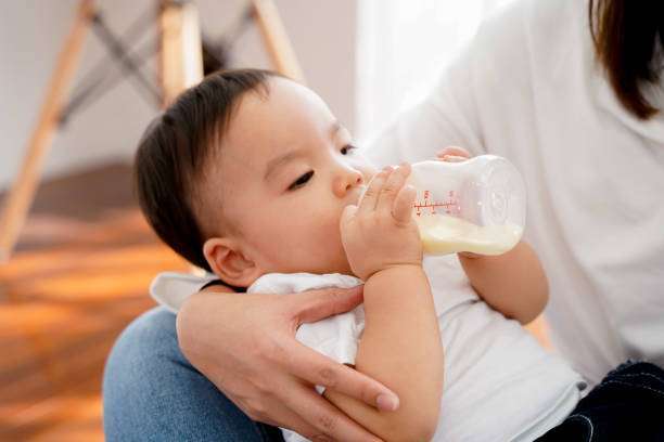 A curly-haired baby girl uses a bottle warmer.