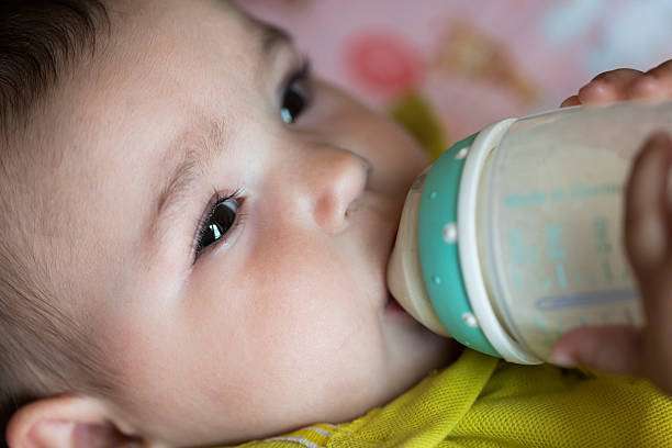 toddler baby girl drinking milk from a bottle warmer