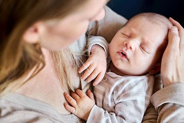 Close-up of caring mother lovingly holding her newborn's .bottle warmer