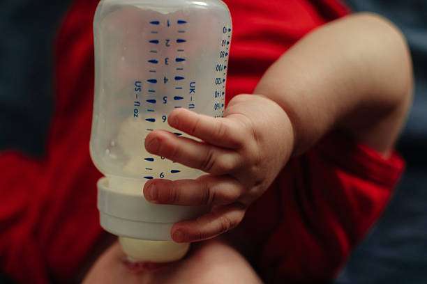 Young daughter lying on sofa drinking milk.bottle warmer