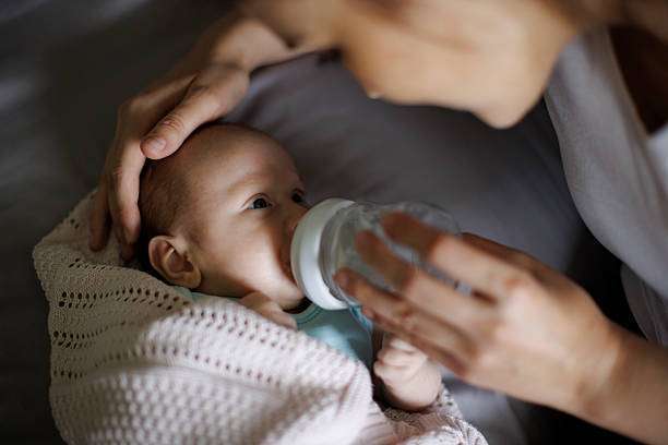 A curly-haired baby girl uses a bottle warmer.