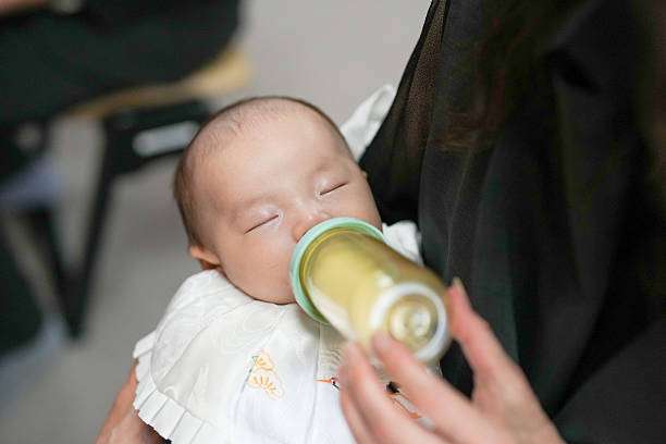 A curly-haired baby girl uses a bottle warmer.